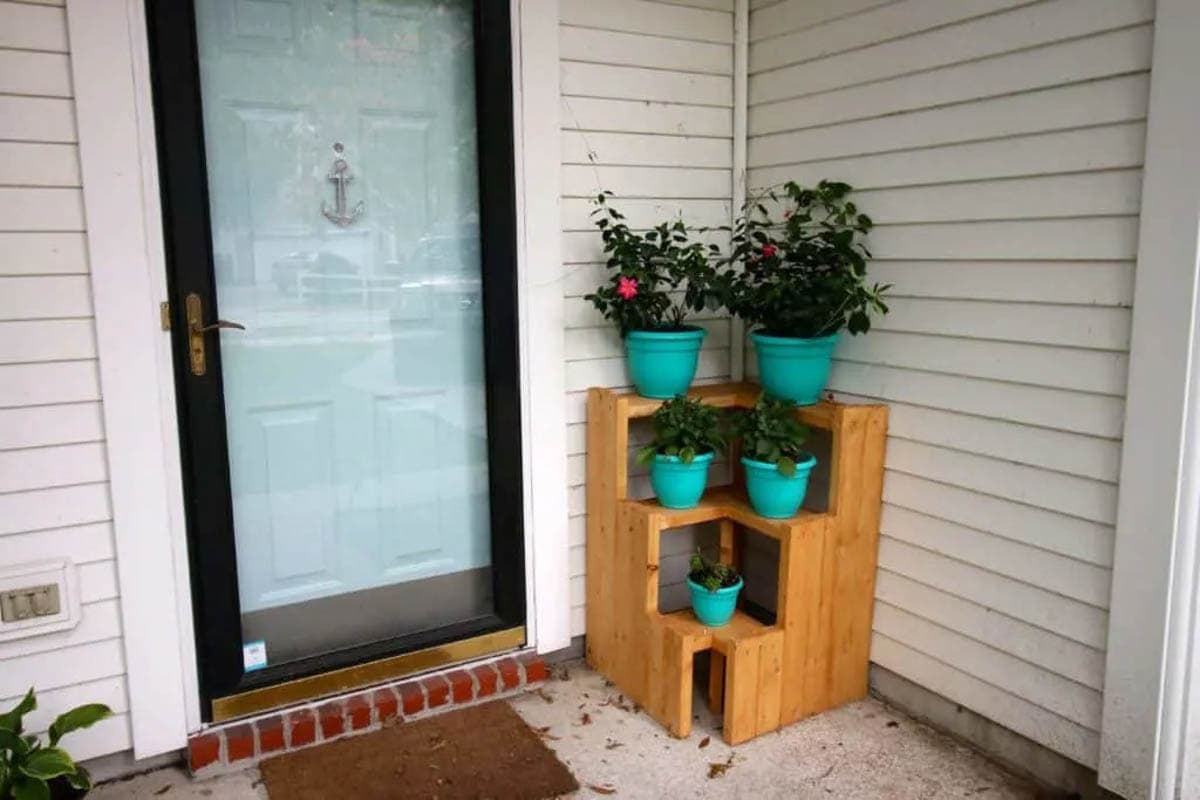 Corner plant stand on porch with flowers in teal colored pots
