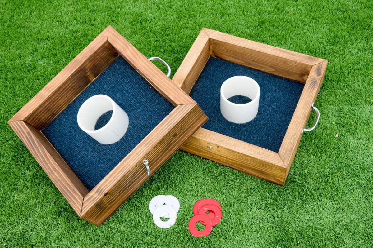 Washer toss game boards made from 2x4s sitting on the grass