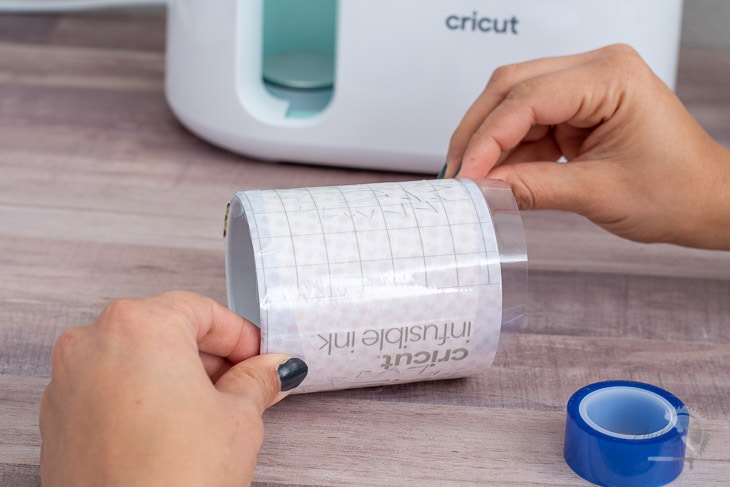 Woman applying tape to the design for the Cricut Mugpress