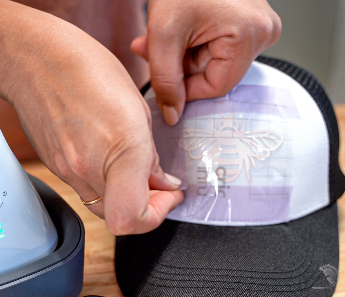 woman applying strong heat resistant tape around design on hat