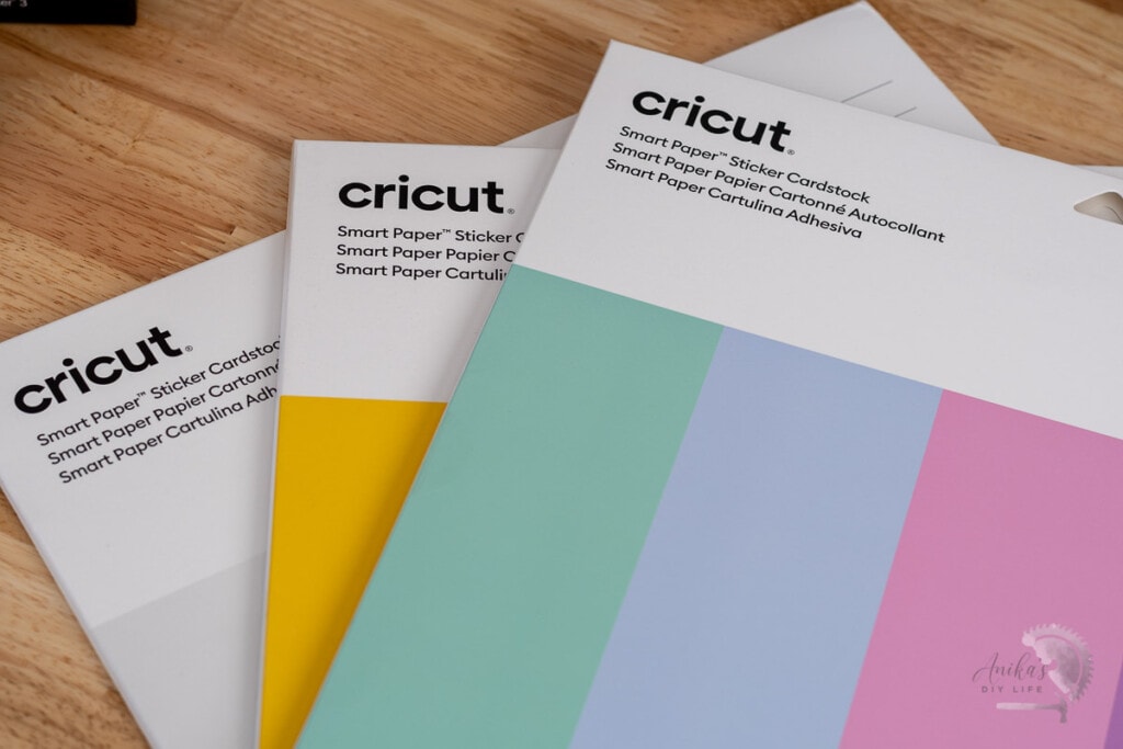 Cricut Smart Paper Sticker Cardstock on table in three colors