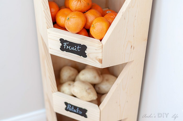 close up of corner vegetable storage bin with oranges and chalkboard label