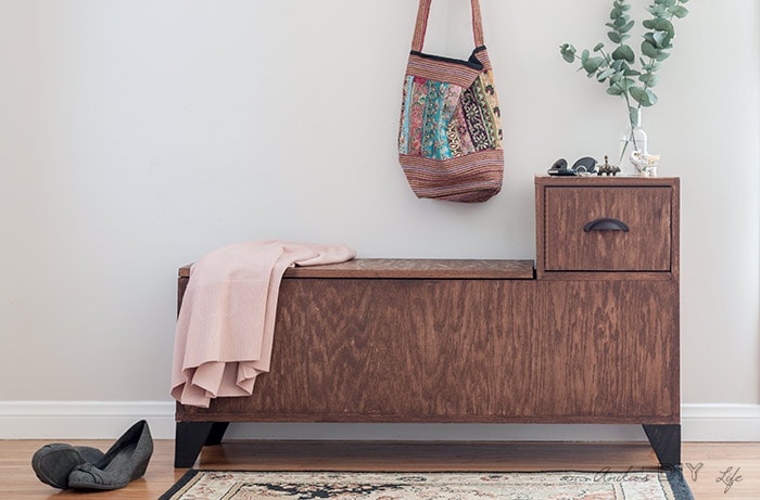 DIY entryway bench with storage styled with plant, shoes, jacket and bag.
