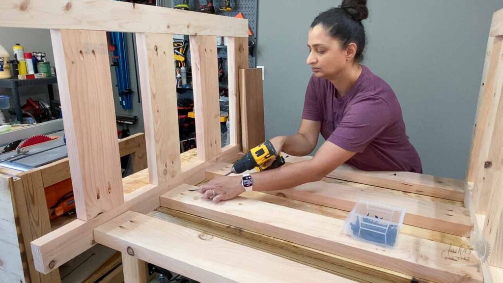 Woman building attaching all the slats to build the leg frame using pocket hole screws