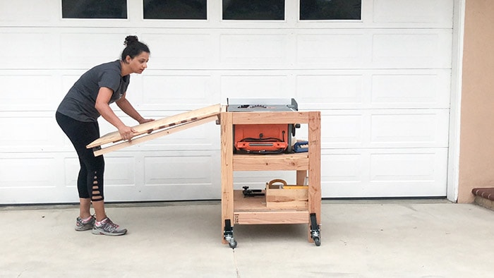 Woman folding the outfeed table of the DIY table saw stand