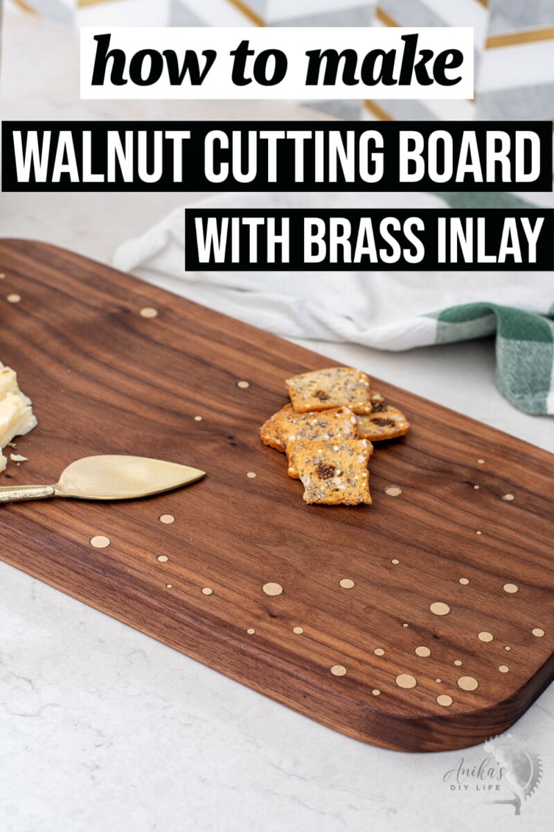 DIY Walnut cutting board with brass rod inlay with cheese and crackers on counter