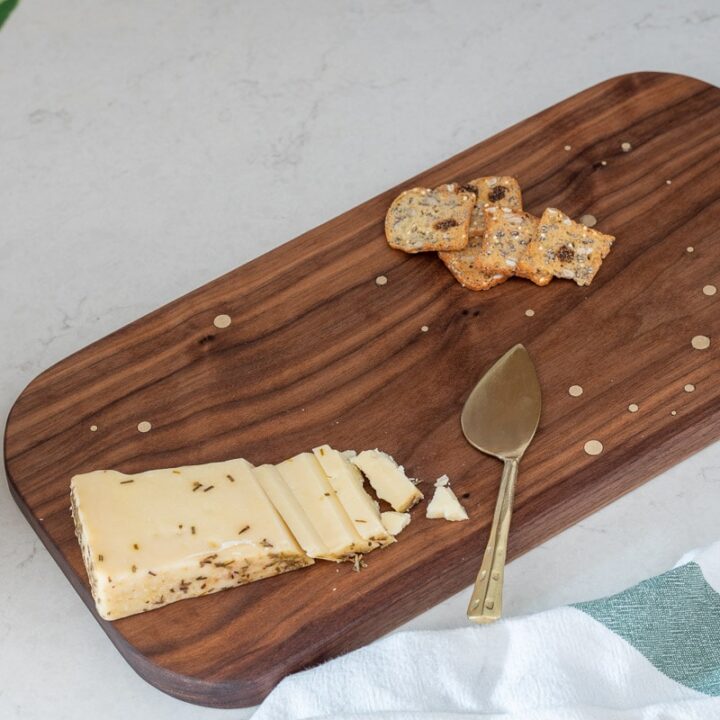 DIY walnut cutting board with brass inlay with cheese and crackers