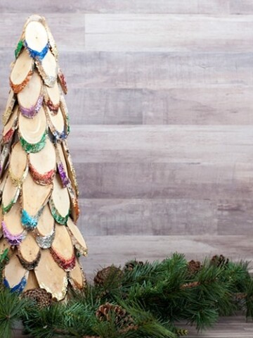 This colorful wood slice Christmas tree is the perfect DIY wooden Christmas decoration. Add lots of bright sparkle to your mantle or doorstep!