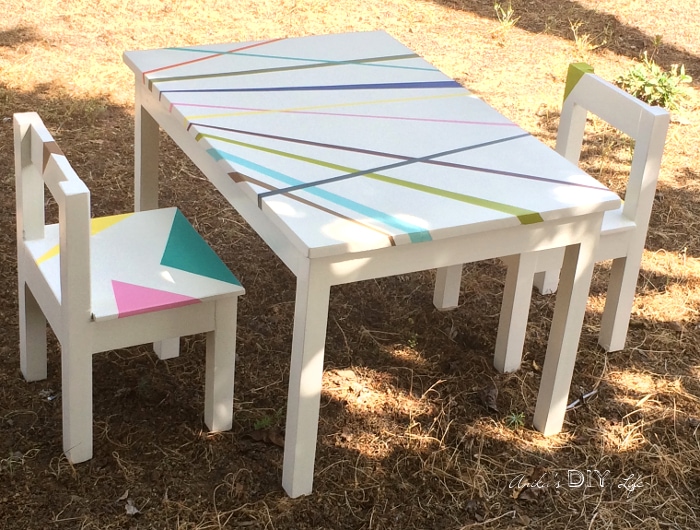 White DIY kids table and chair with colorful stripes in back yard