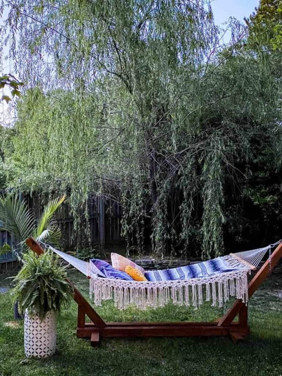 dark stained DIY hammock stand with pillows and macrame fringed hammock