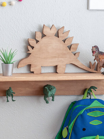 Dinosaur shelf with dinosaur hooks with small plant, T-rex and a bag