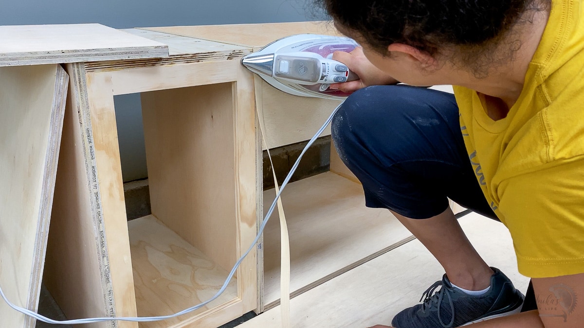 woman applying edge banding to an assembled piece of furniture