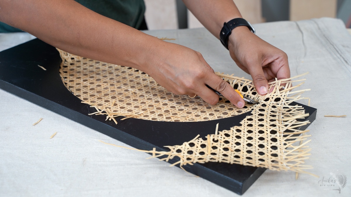 cutting off excess cane webbing with utility knife
