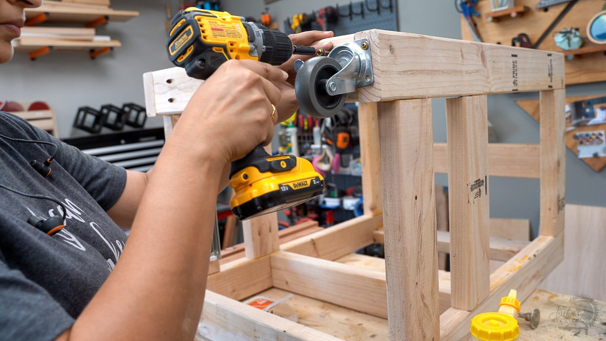 Woman attaching casters to the bottom of the 2x4 frame