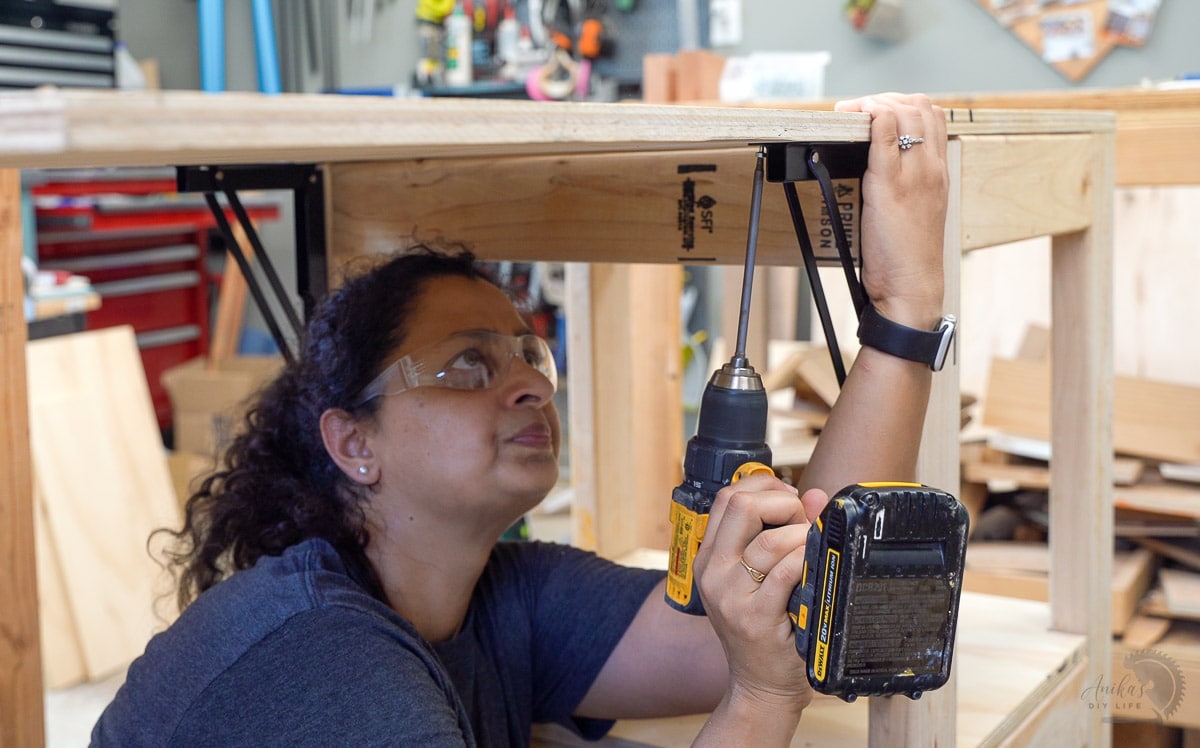 Woman attaching folding table brackets to the planer stand