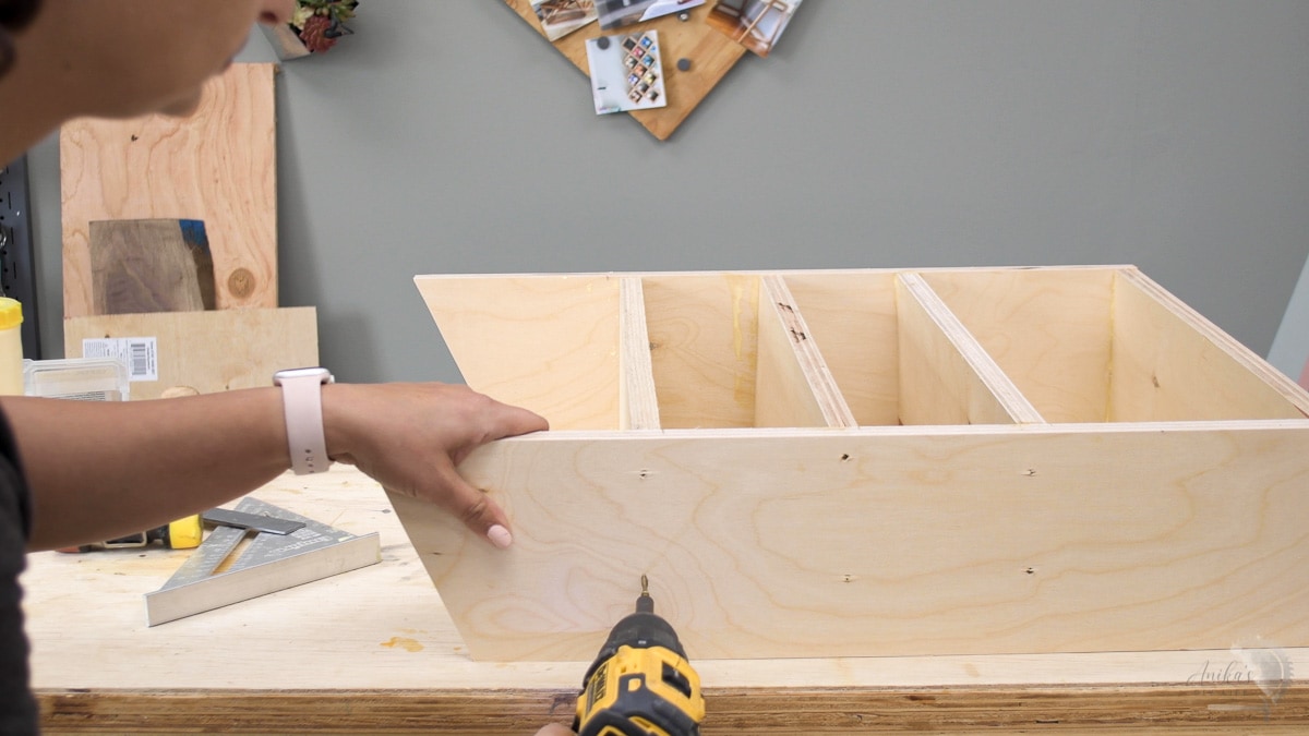 woman attaching shelves in sandpaper organizer with screws. 