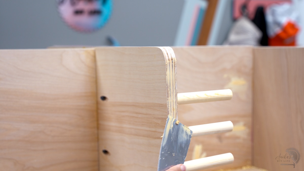 Applying wood filler to the edge of the plywood using a putty knife