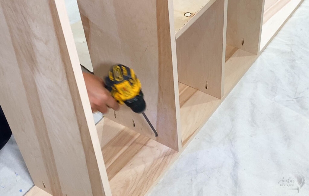 woman attaching a drawers and shelf to the plywood to build the closet organizer