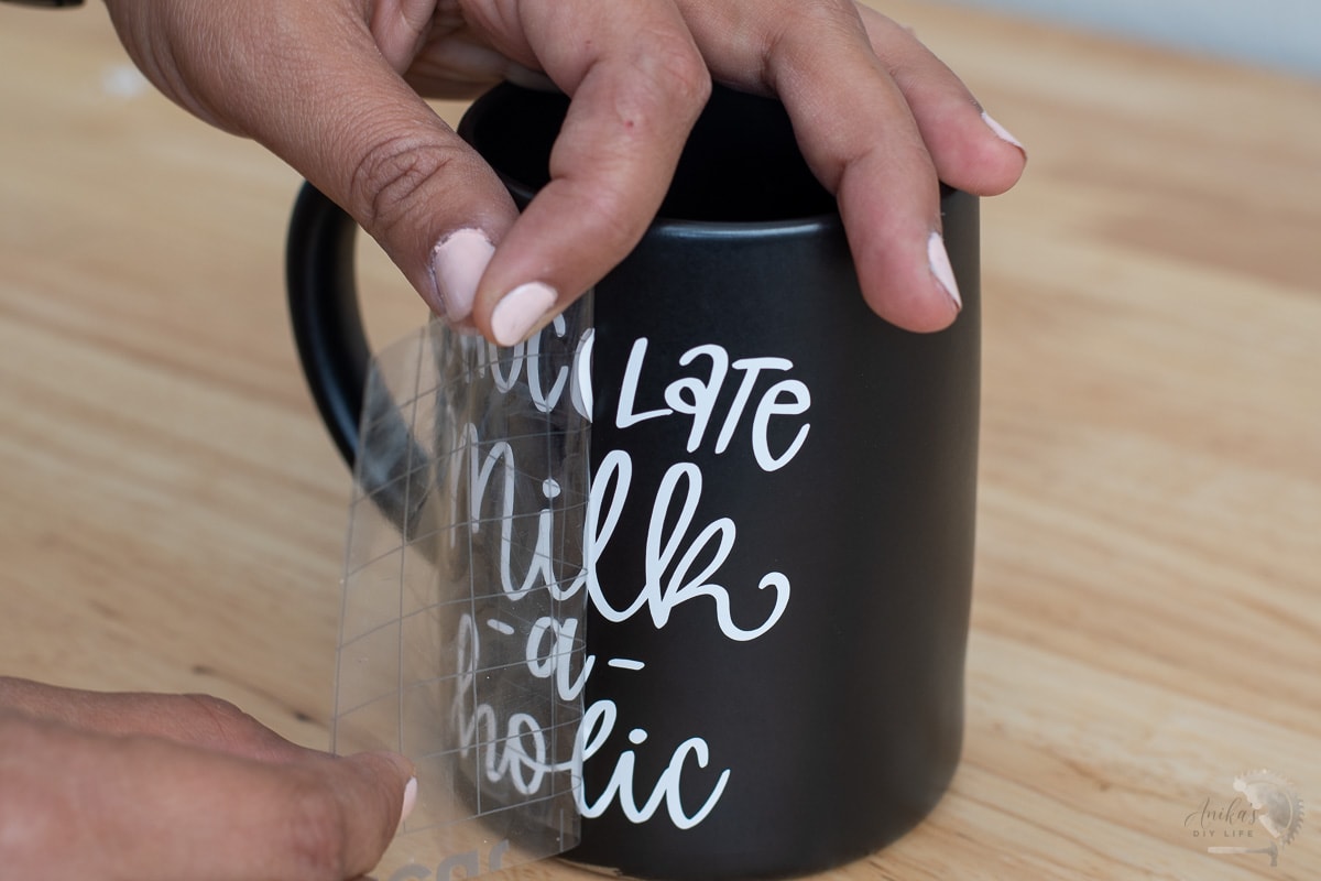 Applying white vinyl lettering design to mug