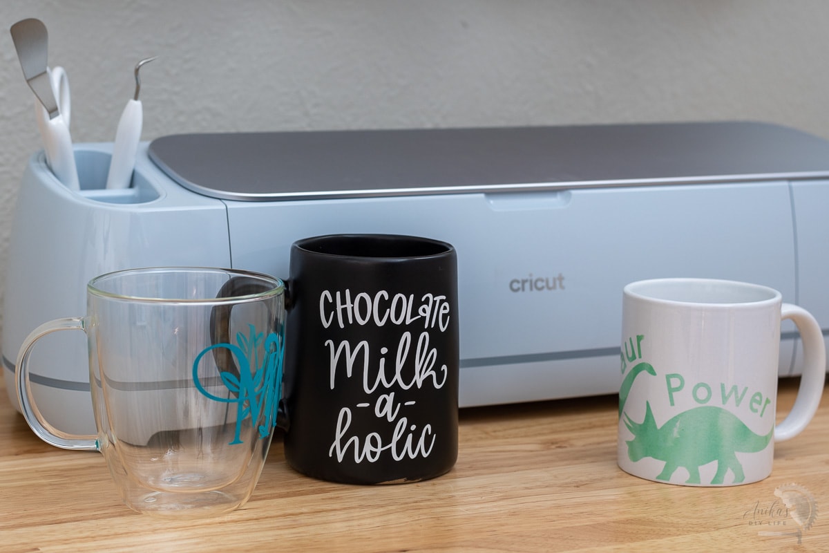 Cricut Machine on table with three mugs made in various ways