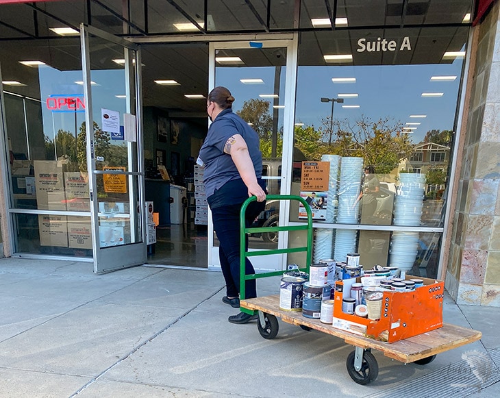 woman rolling away paint in a cart for recycling