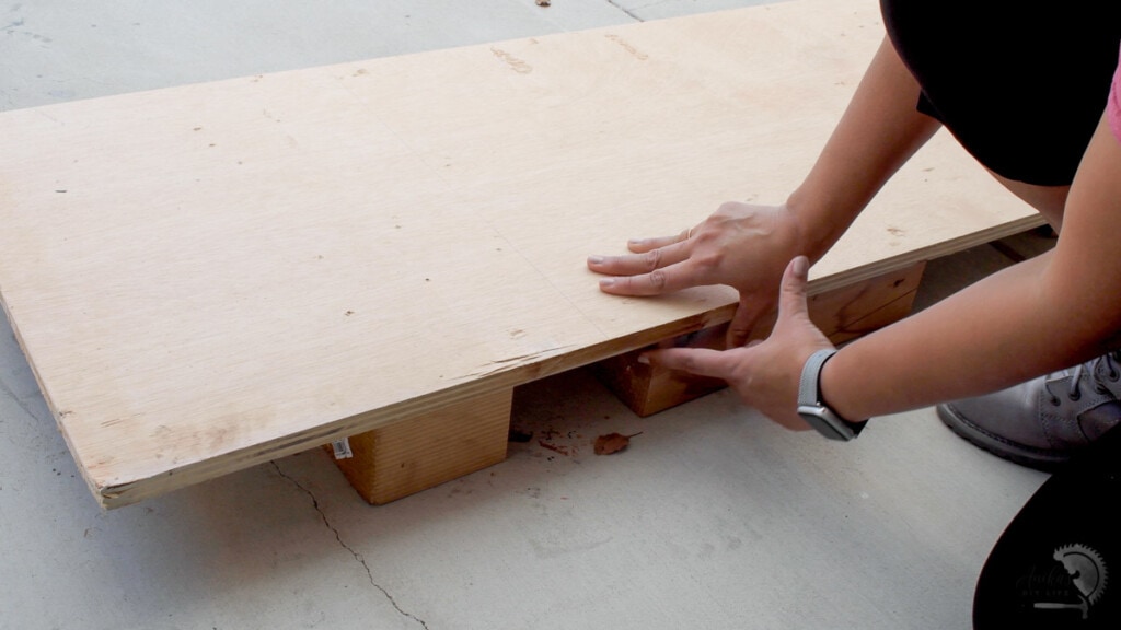 woman setting up plywood to cut on the floor with 4x4 blocks