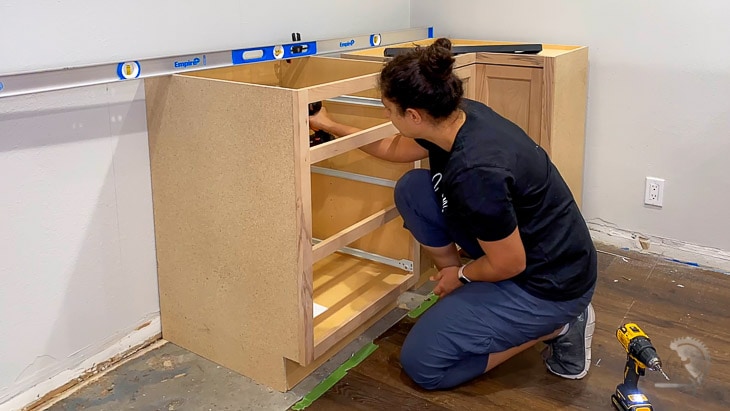 woman installing base cabinets in the kitchen