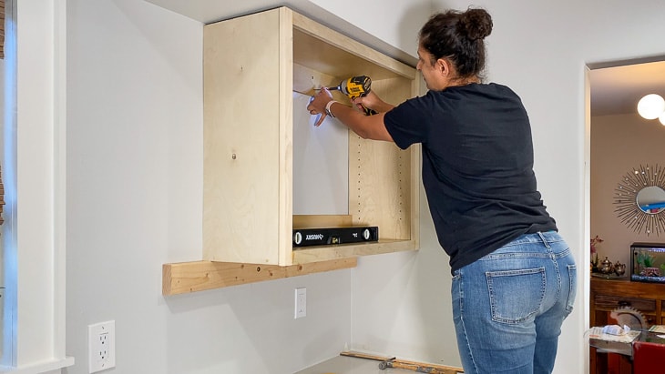 woman installing upper cabinets