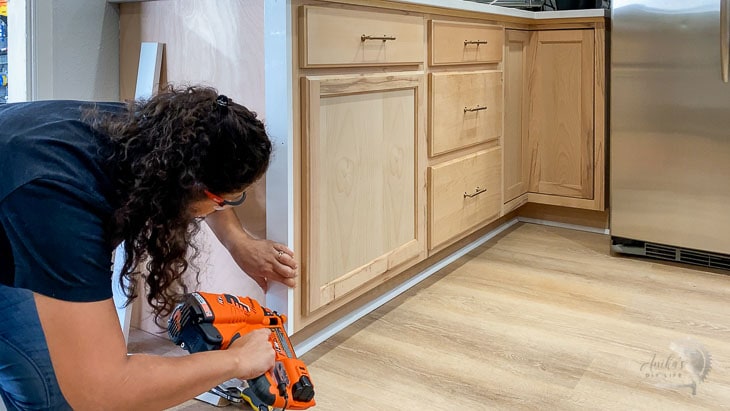 woman installing trim on the side of the cabinet
