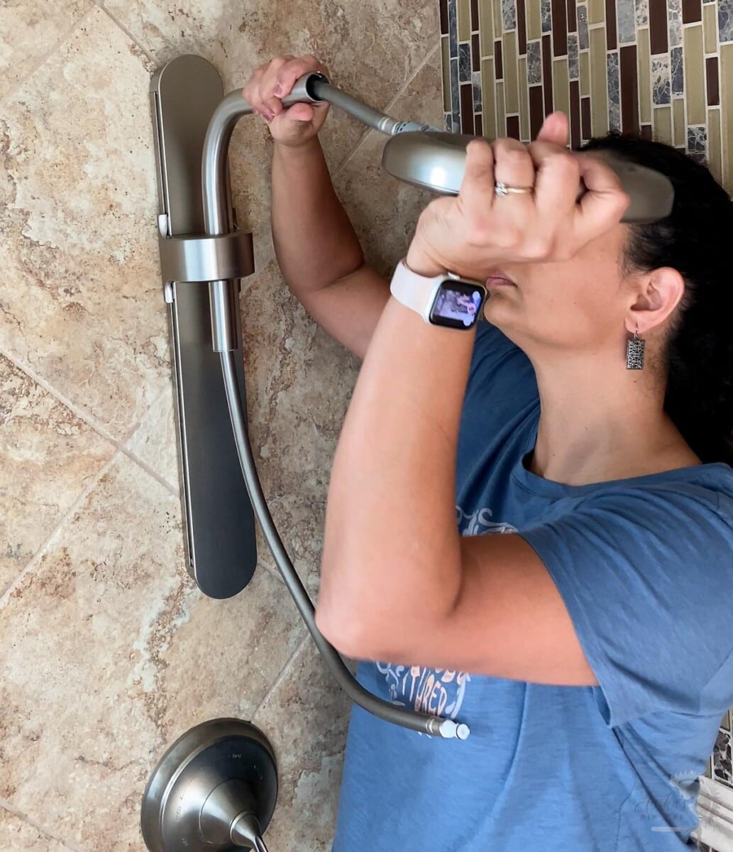Woman attaching the shower head into the shower arm