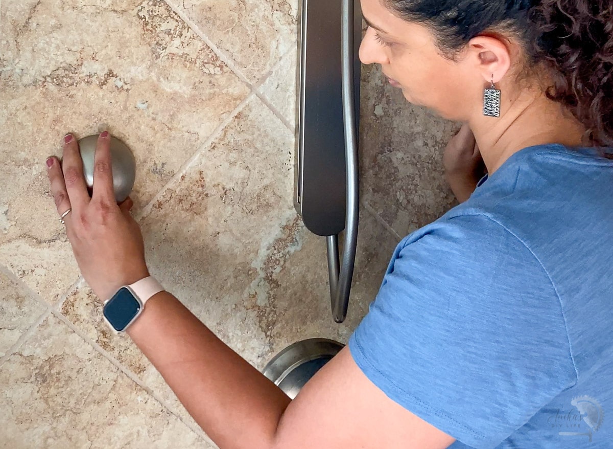 woman attaching the magnetic handshower hold to the wall
