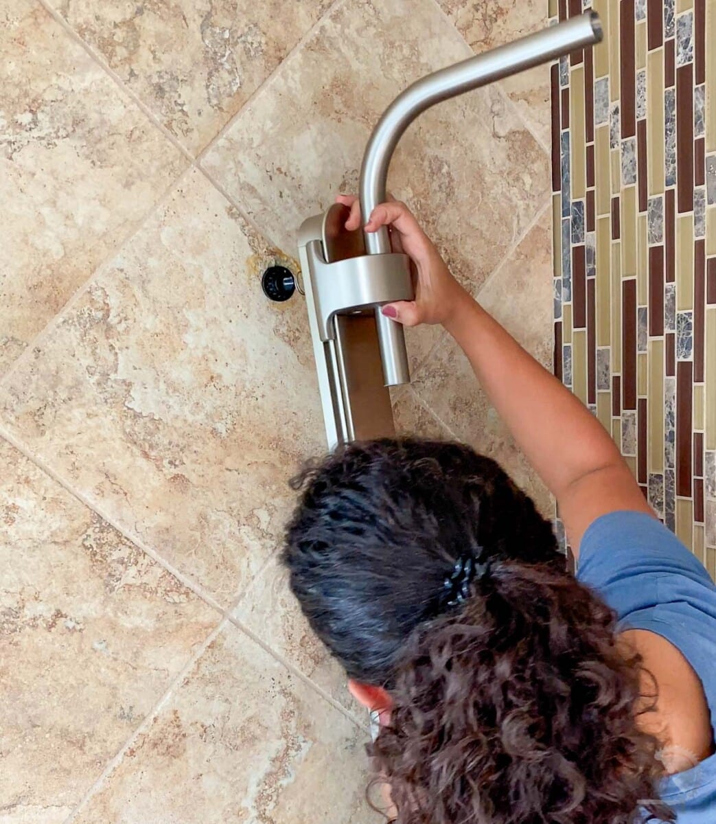 woman attaching the shower into the wall
