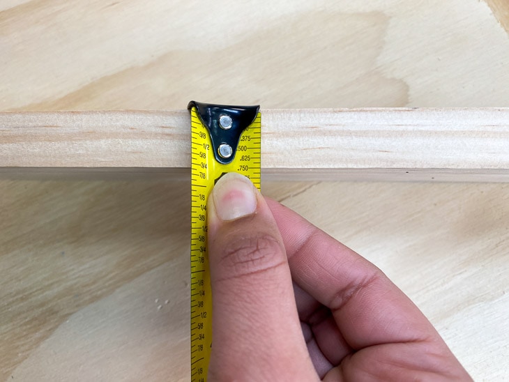 Measuring thickness of board with measuring tape before pocket holes